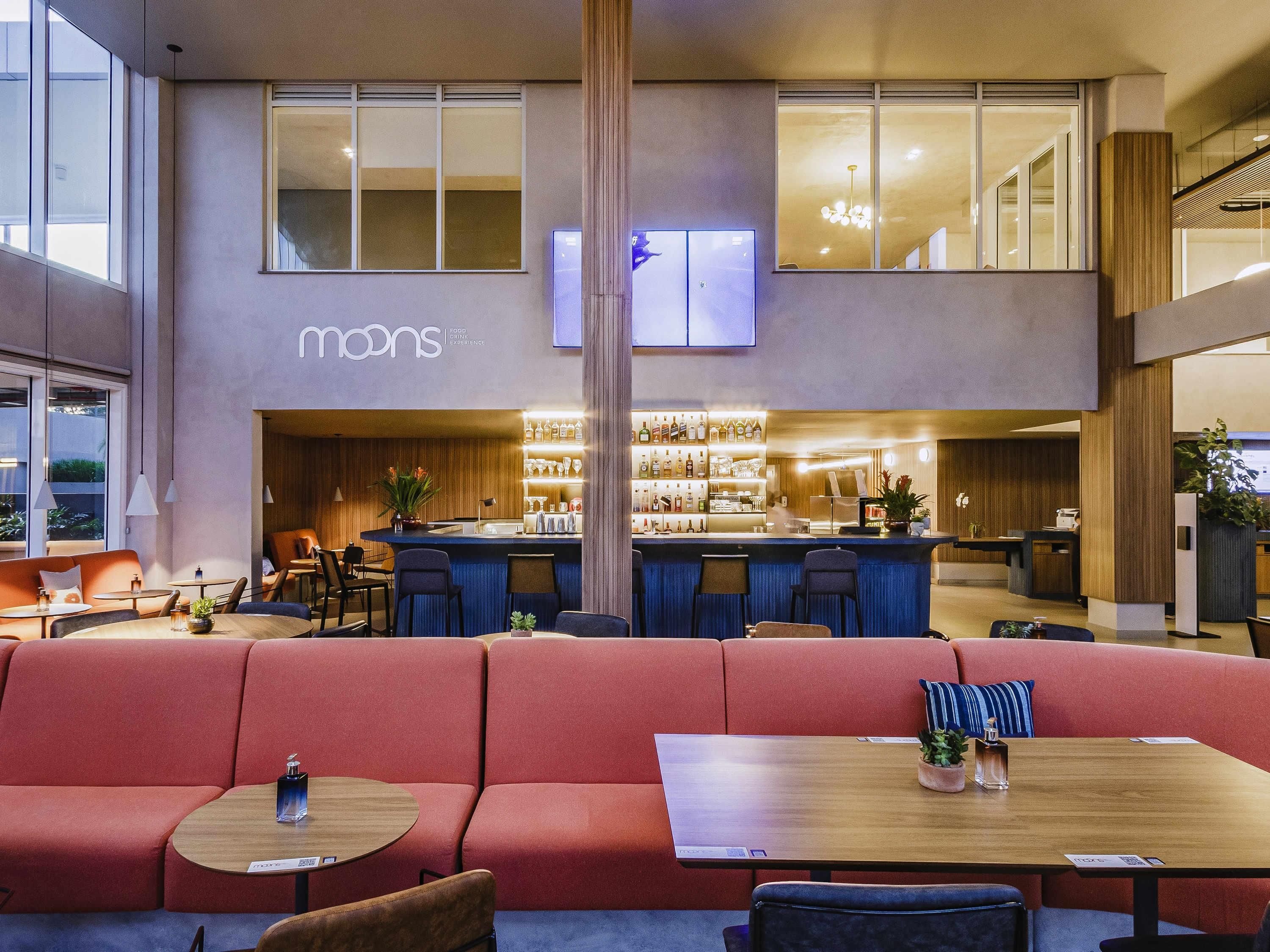A modern hotel lobby with a bar area, seating, and a large window.