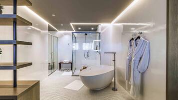 A modern bathroom with a freestanding bathtub, glass shower enclosure, and a towel rack with robes.