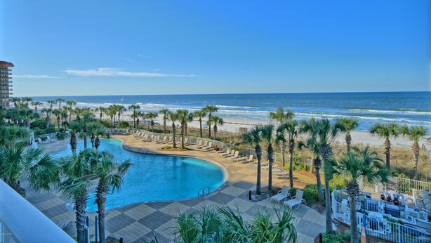 A resort pool with a view of the beach and ocean.