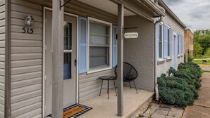 Ein Wohngebäude mit einer Veranda, Hausnummer 515, mit Fußmatte, einem Stuhl und einem Schild mit der Aufschrift 'welcome'.