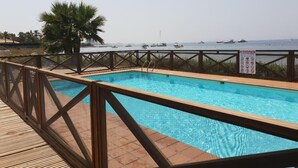 Une piscine avec une terrasse en bois et vue sur la mer.