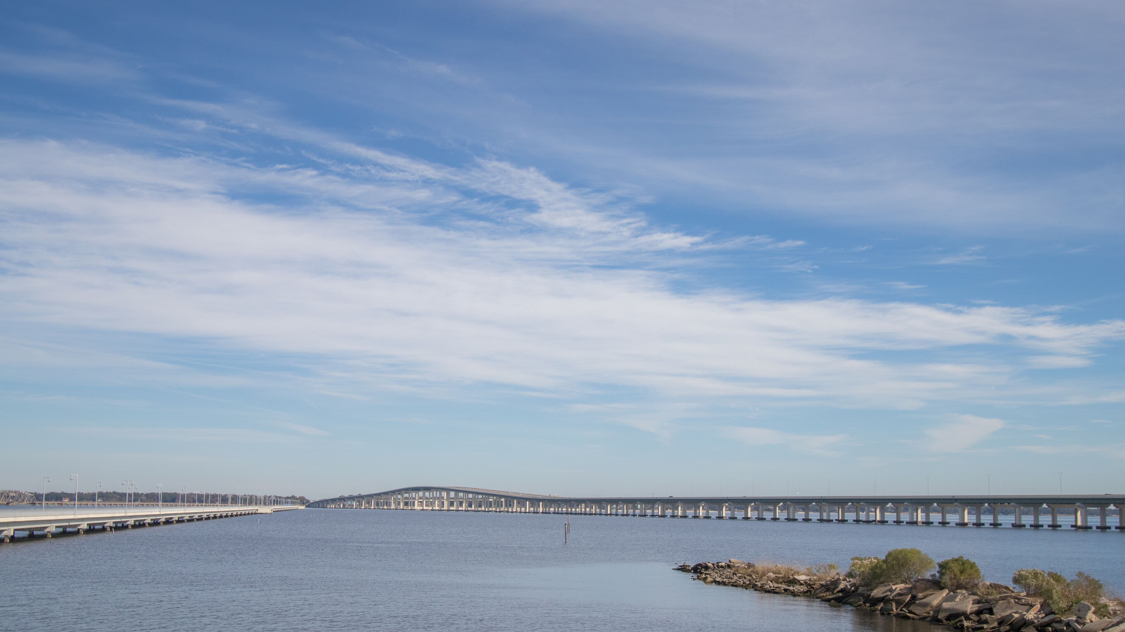 A long bridge over a calm body of water with a clear sky.