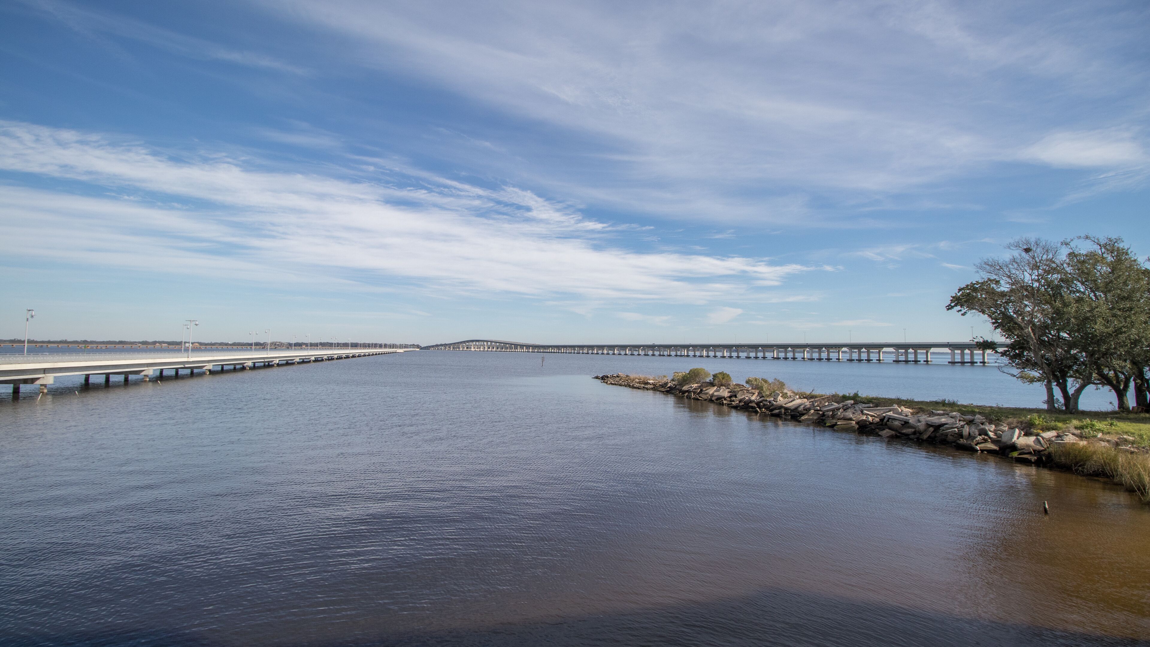 A long bridge over calm water with a clear sky.
