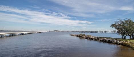 A long bridge over calm water with a clear sky.