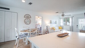 Una habitación luminosa y bien iluminada con zona de comedor, sofá y encimera de cocina.
