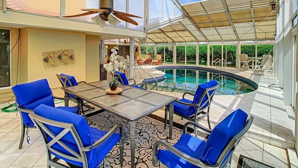 An indoor pool area with a glass ceiling, blue chairs, and a table with a potted plant. - Waterfront  (Clearwater)