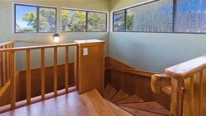 A wooden staircase with a handrail and a light fixture above it. - Large Home in Waikoloa Village | 5-Bedrooms | Newly Updated with AC (Waikoloa)