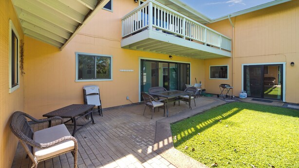 A patio with outdoor furniture, a covered seating area, and a small lawn.