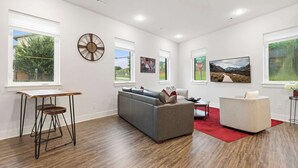 A modern living room with a sofa, a coffee table, a side table, and artwork on the walls. - Razorblock South - 1 mi from DT - 3 blocks to UofA (Fayetteville)
