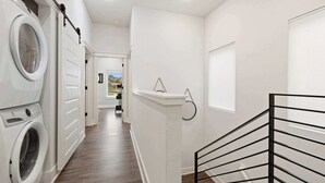 A laundry room with a washing machine, a drying rack, and a staircase with a black railing. - Razorblock South - 1 mi from DT - 3 blocks to UofA (Fayetteville)