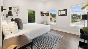A modern bedroom with a bed, a ceiling fan, a black and white striped rug, and a large window with a view. - Razorblock South - 1 mi from DT - 3 blocks to UofA (Fayetteville)