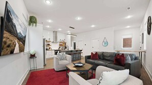 A modern living room with a sofa, coffee table, and a red rug. - Razorblock South - 1 mi from DT - 3 blocks to UofA (Fayetteville)
