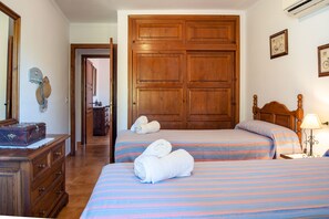Classic hotel room with two single beds, a wardrobe, and a dresser.