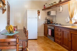 Enjoy meals in this kitchen with a dining table for four, a refrigerator, microwave, oven, and sink.