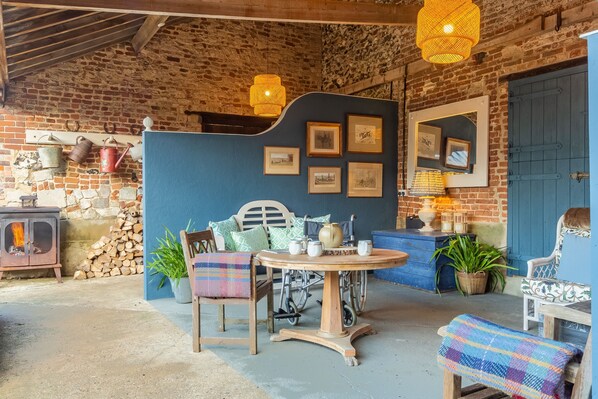 Een rustiek interieur met een stenen muur, houten meubels en een blauwe accentmuur met ingelijste foto's.