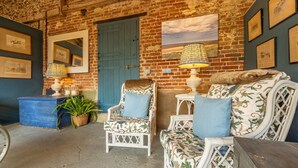 A rustic room with a brick wall, a blue door, and a white chair with a floral pattern. - The Able Stables - Sam's Cottage, East Rudham, Norfolk (East Rudham)