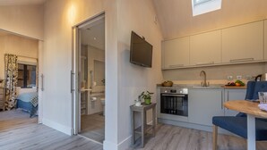 A modern kitchen with a built-in oven, a dining area with a table and chairs, and a small side table with a plant. - The Able Stables - Sam's Cottage, East Rudham, Norfolk (East Rudham)
