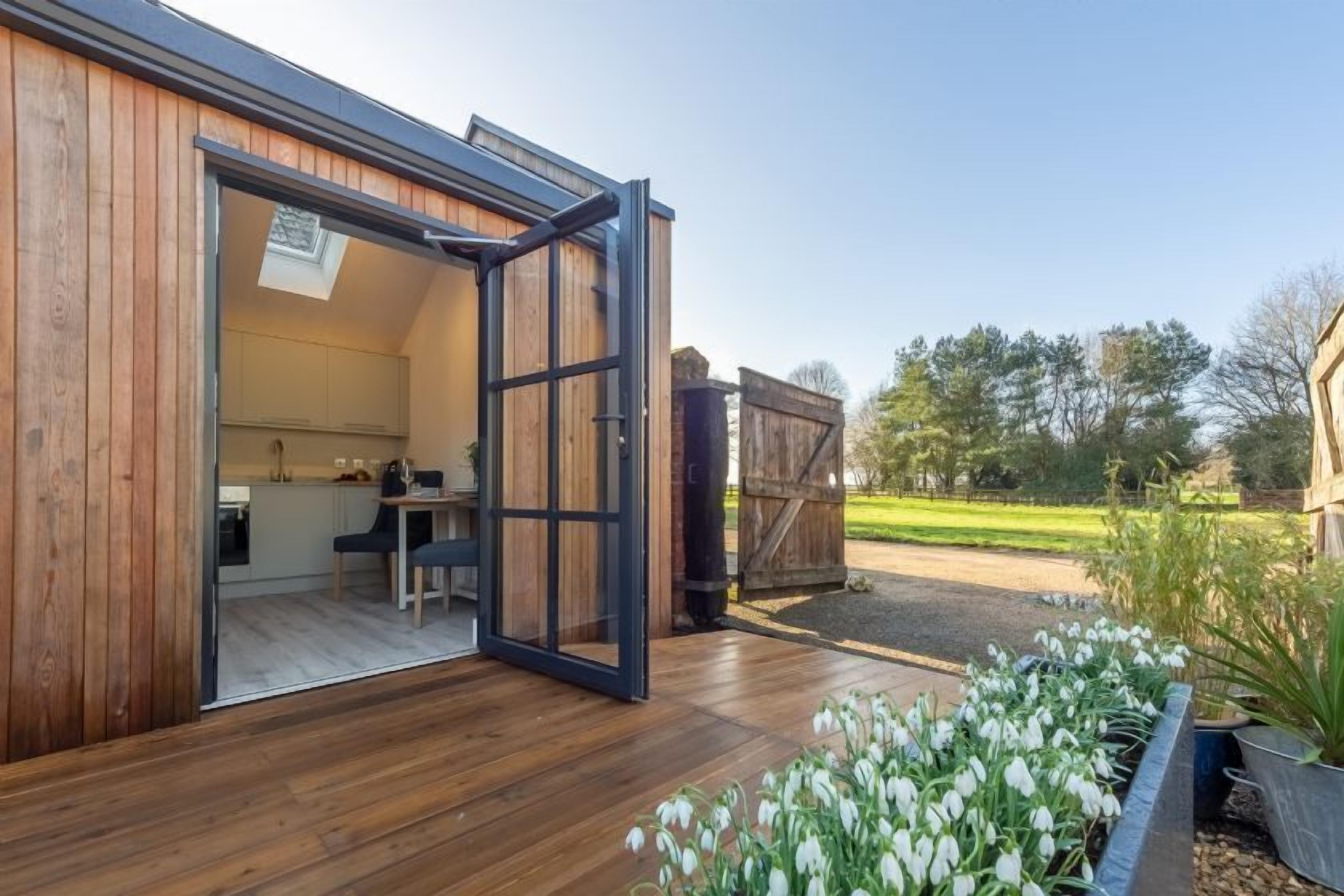 Un edificio moderno de madera con un amplio ventanal abierto que da a una cocina.