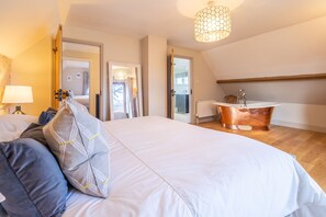 Ein Schlafzimmer mit einem großen Bett, einem Badezimmer mit einem Kupferspülbecken und Blick ins Freie.