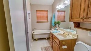 Un baño pequeño con bañera, lavamanos y muebles de madera.
