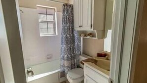 A small bathroom with a toilet, a sink, and a shower area. - Spacious 3BR Ranch |Pet-Friendly |Near ExpoCenter (Broken Arrow)