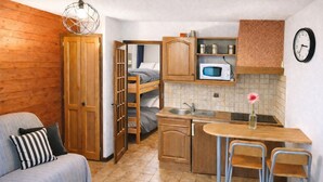 Ein kleines Zimmer mit Küchenzeile, einem Bett, einer Schlafcouch und einem Essbereich.