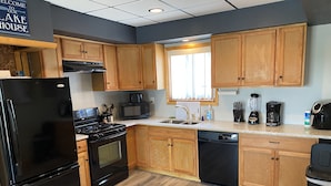 A modern kitchen with wooden cabinets, a black refrigerator, a stove, a microwave, and a dishwasher. - Water Front Vacation Home (Clay Township)