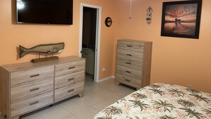 Una camera da letto con un letto, una cassettiera, una televisione e una ventola a soffitto.