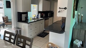 Una cucina moderna con mobili bianchi, un piano di lavoro nero e un'area pranzo con tavolo e sedie.