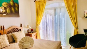 A hotel room with a bed, a nightstand, a lamp, a chair, and a painting of coconuts. - 2 connected villas 19 Pax (Playa del Carmen)