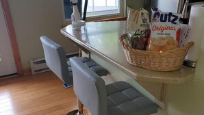 A kitchen with a bar area, a refrigerator, and a window with a view of trees. - Cottage on Lake Erie with beach access .Local wineries (North East)