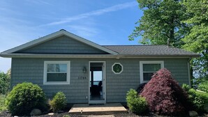 A single-story house with a grey siding exterior, a front door, and a small porch. - Cottage on Lake Erie with beach access .Local wineries (North East)