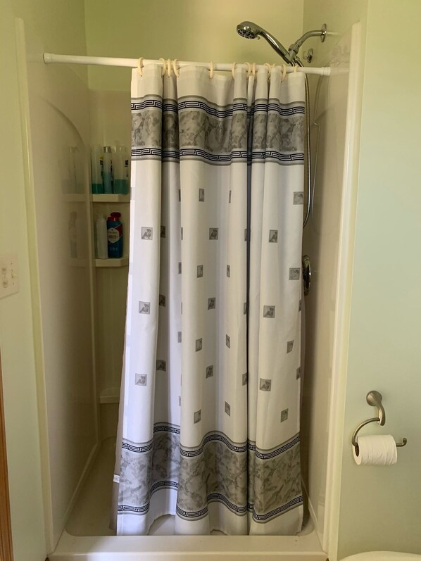 A shower area with a white shower curtain featuring a marble pattern and a decorative border.