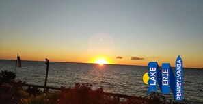 A sunset over a body of water with a sign indicating Lake Erie and Pennsylvania. - Cottage on Lake Erie with beach access .Local wineries (North East)
