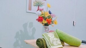 Un petit coin repas comprenant une table, des chaises, un vase de fleurs et une fenêtre ornée d’un tableau.