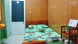 Une petite pièce, de taille modeste, comprenant un lit, une valise et une petite table sur laquelle est posée une plante.