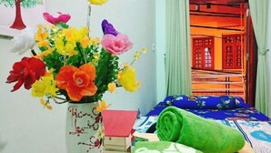 Une pièce avec un lit, une serviette verte, une petite boîte et un vase rempli de fleurs colorées.