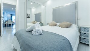 A modern hotel room with a large bed, a bedside table, a mirror, and a view of the dining area. - The Cove of Mogro (Mogro)