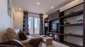 A modern living room with a sofa, a coffee table, and a TV on a shelf. - The Cove of Mogro (Mogro)