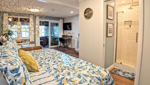 Une chambre avec un grand lit, un bureau et un espace douche.