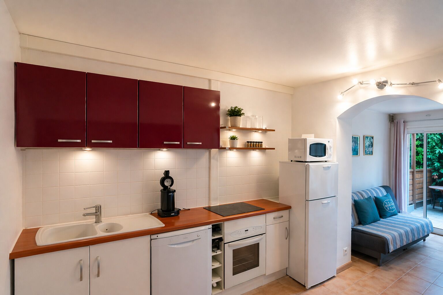 A compact kitchen with white cabinets, a coffee machine, a microwave, and a dishwasher.