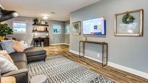 A modern living room with a grey sofa, patterned rug, and a TV mounted on the wall.