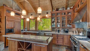 A spacious kitchen with wooden cabinets, a large island, and a stone backsplash. - Mountain Bear Lodge At Northstar - TLUXP (Truckee)
