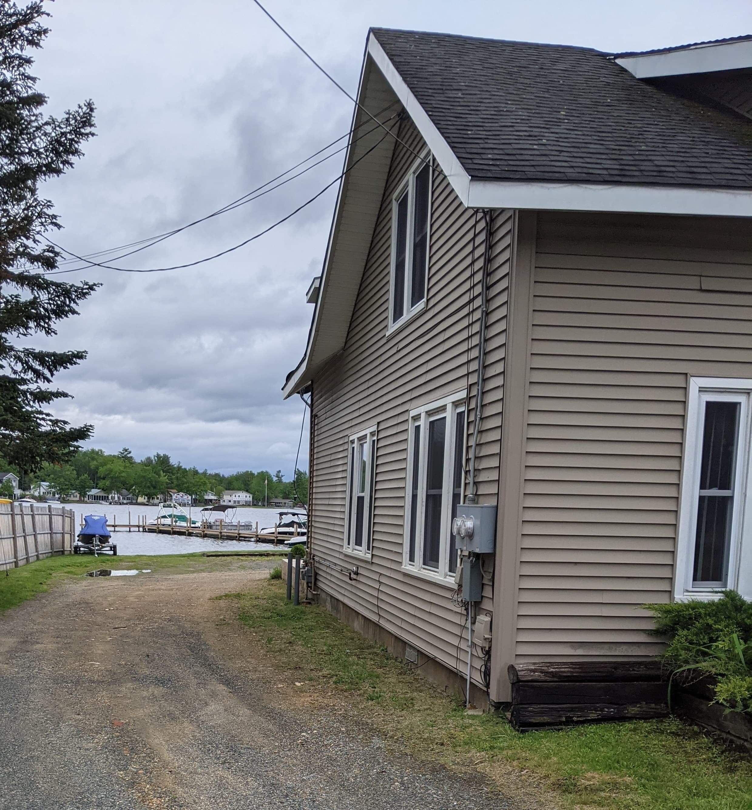 Une maison avec un toit en pente, un garage et une jetée qui s’avance dans l’eau.