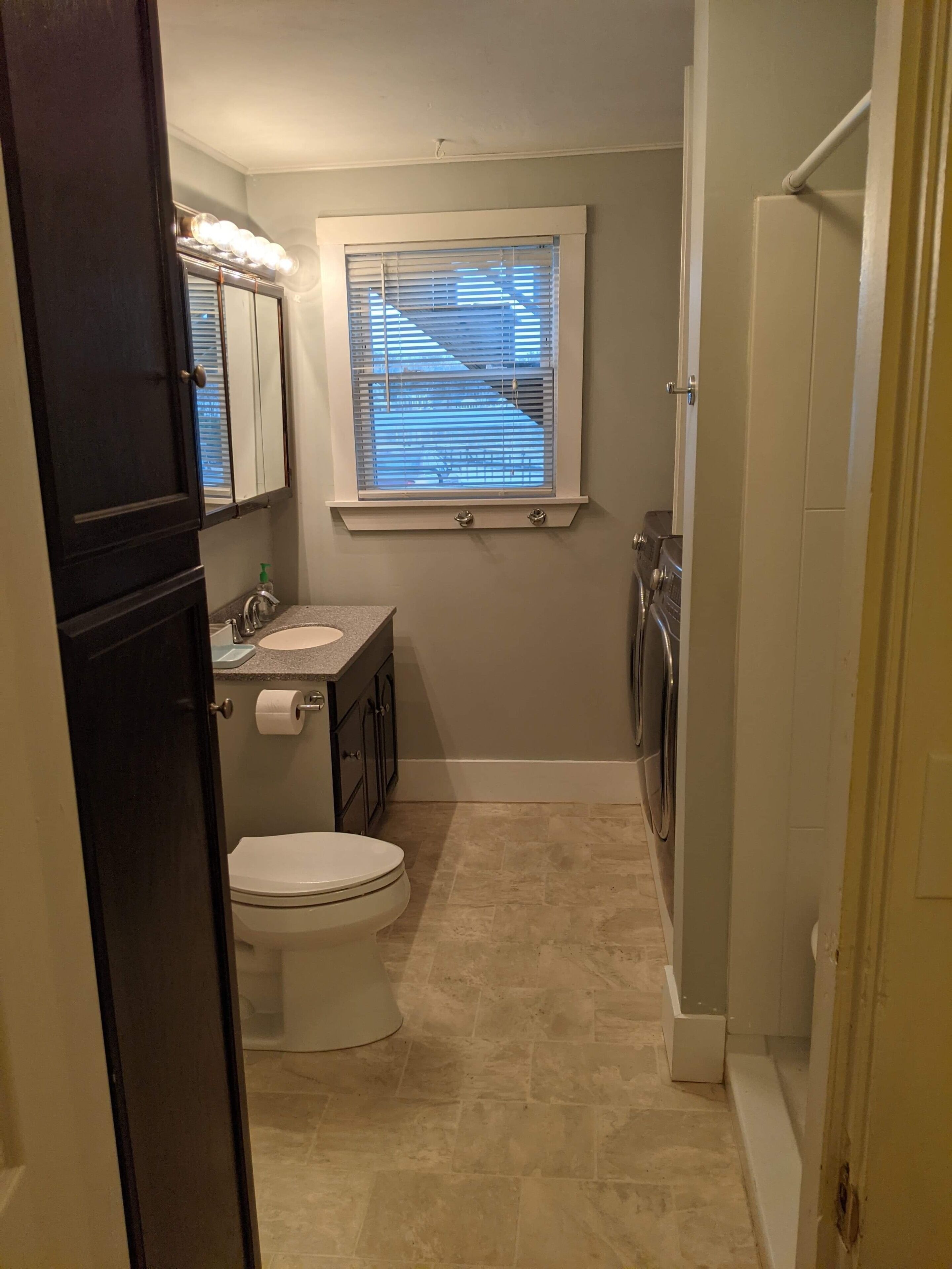 A compact bathroom with a toilet, sink, and mirror.