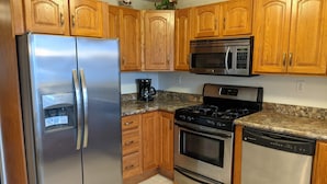 A kitchen with wooden cabinets, stainless steel appliances including a refrigerator, microwave, stove, oven, and dishwasher. - Winnisquam Lakeside Retreat w/Sandy Beach & Boat Docks (Tilton)