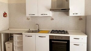 A kitchen with white cabinets, a stainless steel sink, a gas stove, and an oven. - Villa Green a Venticano: Soggiorno sereno nel cuore del Taurasi (Venticano)