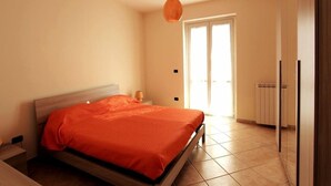 A bedroom with a bed, a hanging light fixture, a door, and a radiator. - Villa Green a Venticano: Soggiorno sereno nel cuore del Taurasi (Venticano)