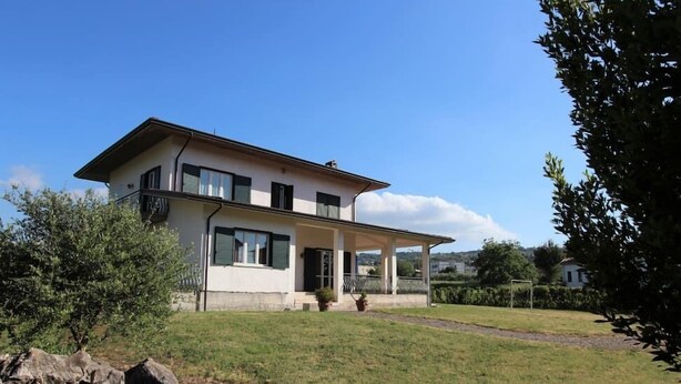 A two-story house with a balcony, a covered porch, and a well-maintained lawn. - Villa Green a Venticano: Soggiorno sereno nel cuore del Taurasi (Venticano)