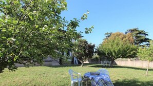 A grassy outdoor area with a table and chairs, a tree, and a building in the background. - Villa Green a Venticano: Soggiorno sereno nel cuore del Taurasi (Venticano)